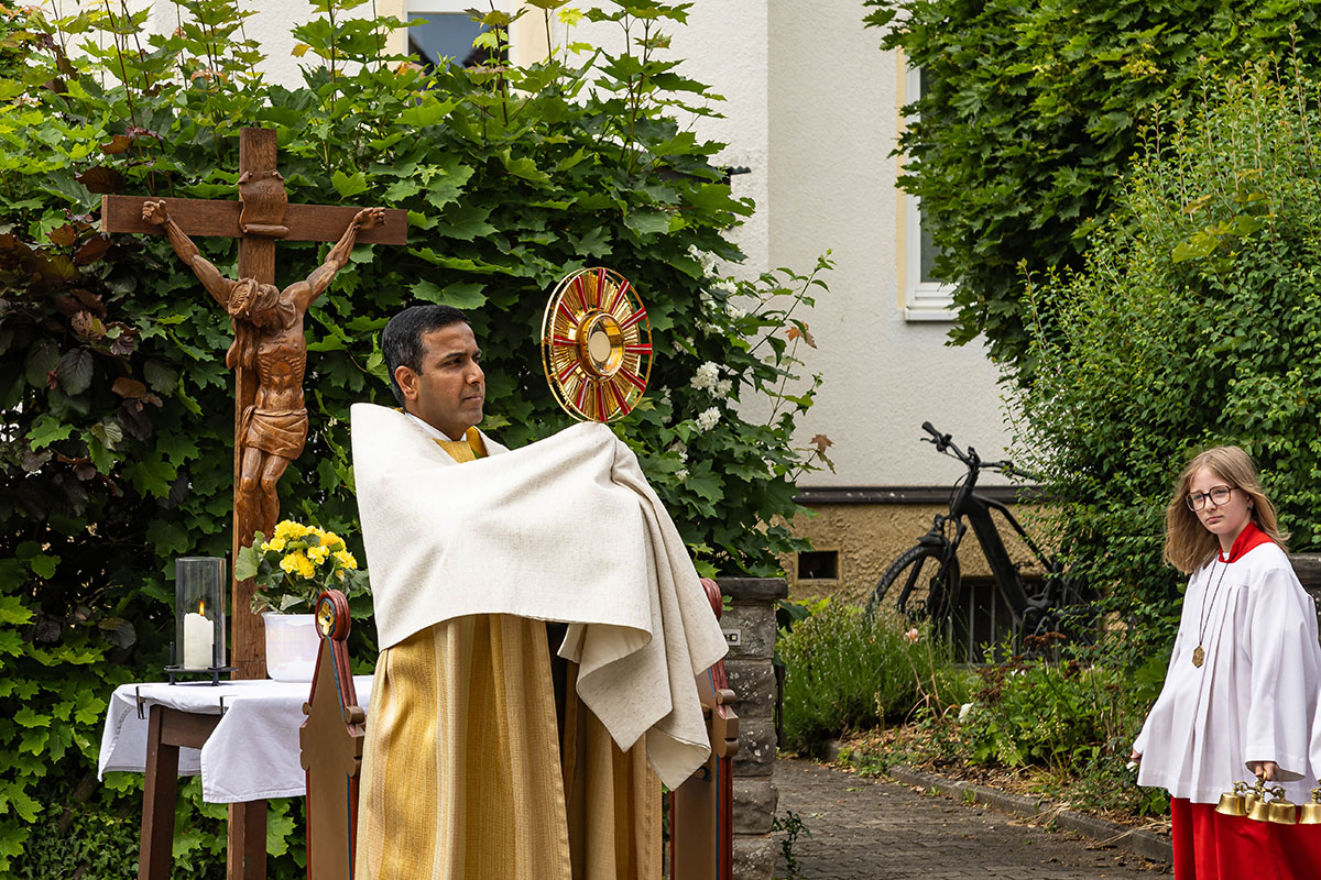 Pfarrvikar Joseph erteilt vor dem vierten Altar den eucharistischen Segen, links hinter ihm der Altar, rechts im Bild eine Ministrantin